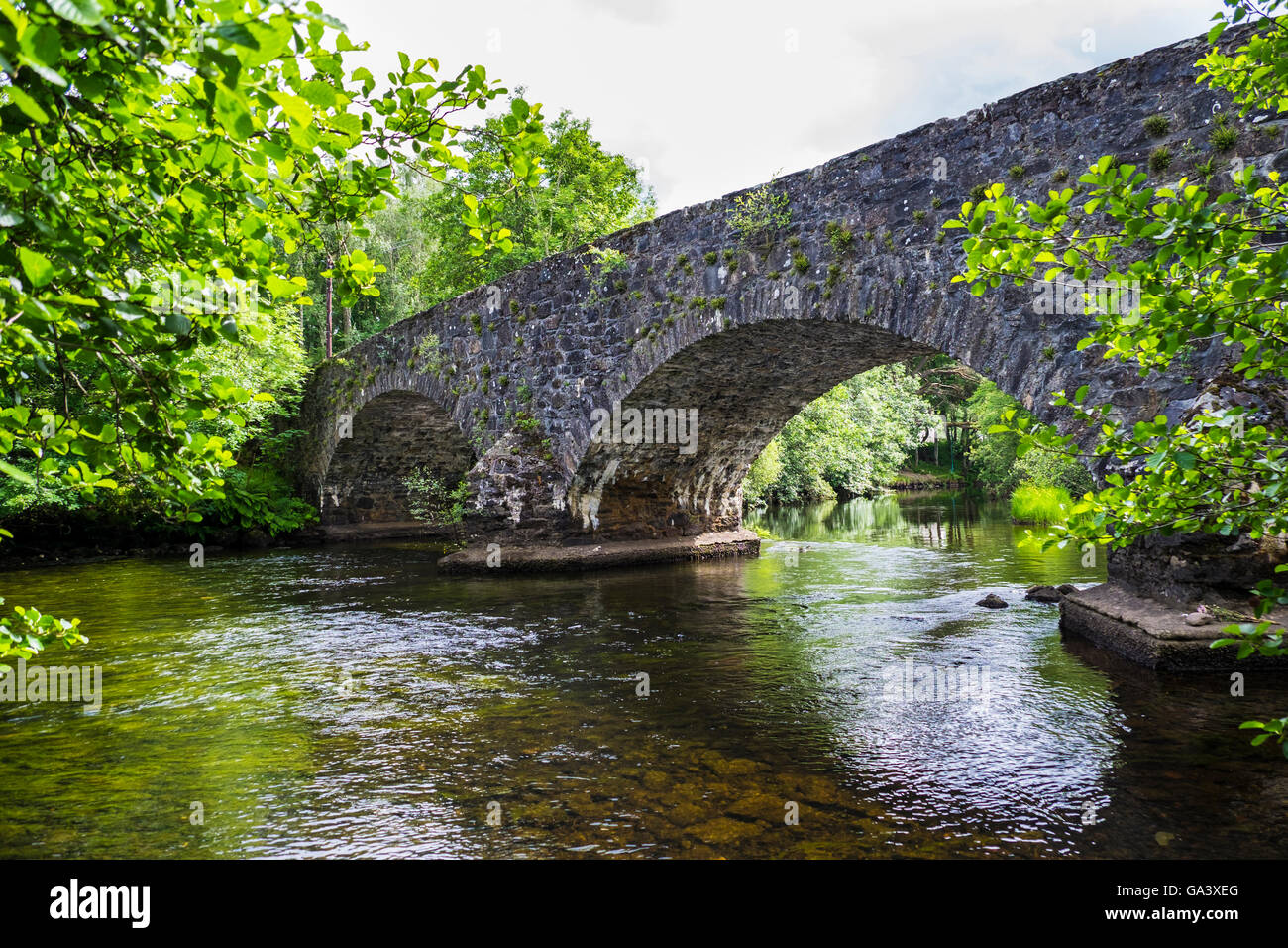 The arches of the stone hump back bridge over the River Balvag at Balquhidder, Scotland. Stock Photo
