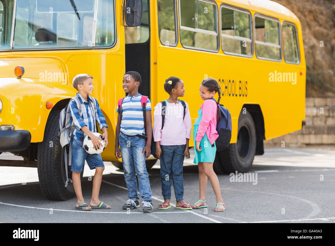 Smiling kids standing together in front of school bus Stock Photo - Alamy