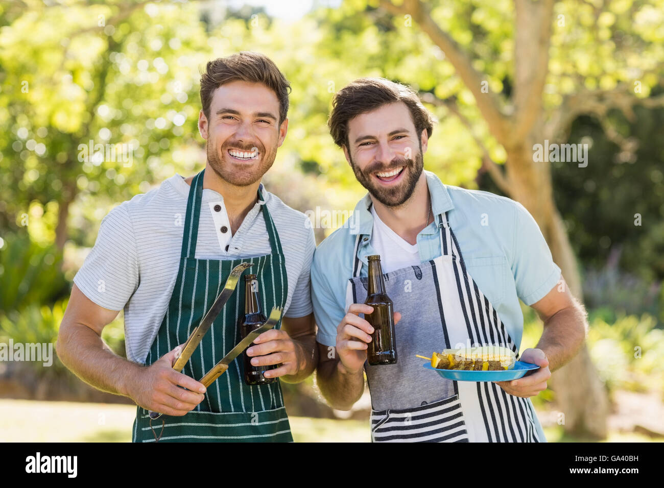 Portrait of two happy men holding barbecue meal and beer