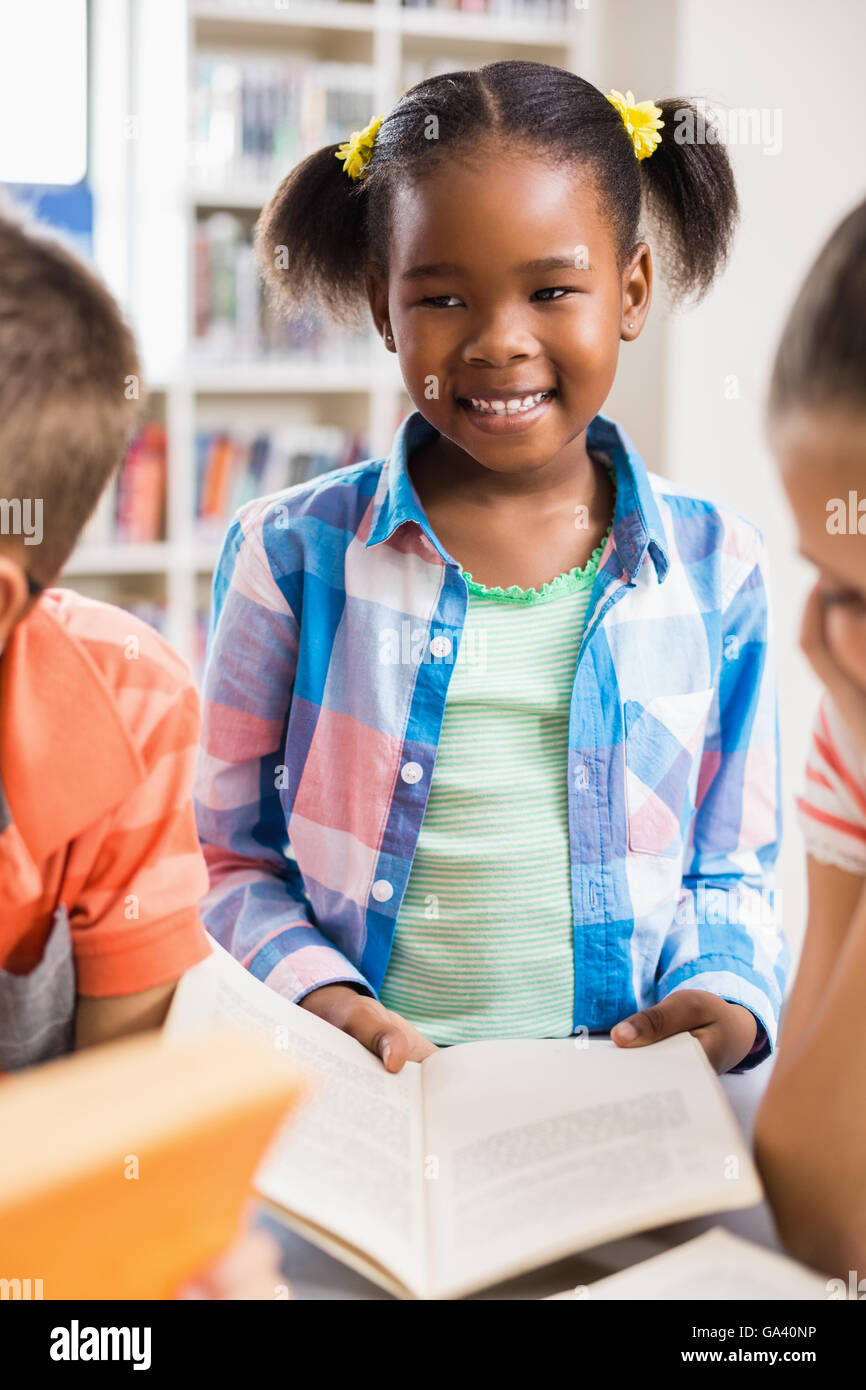 Schoolgirl reading a book in library Stock Photo - Alamy