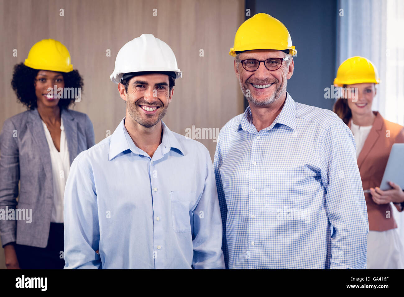 Team of smiling architects standing in office Stock Photo - Alamy