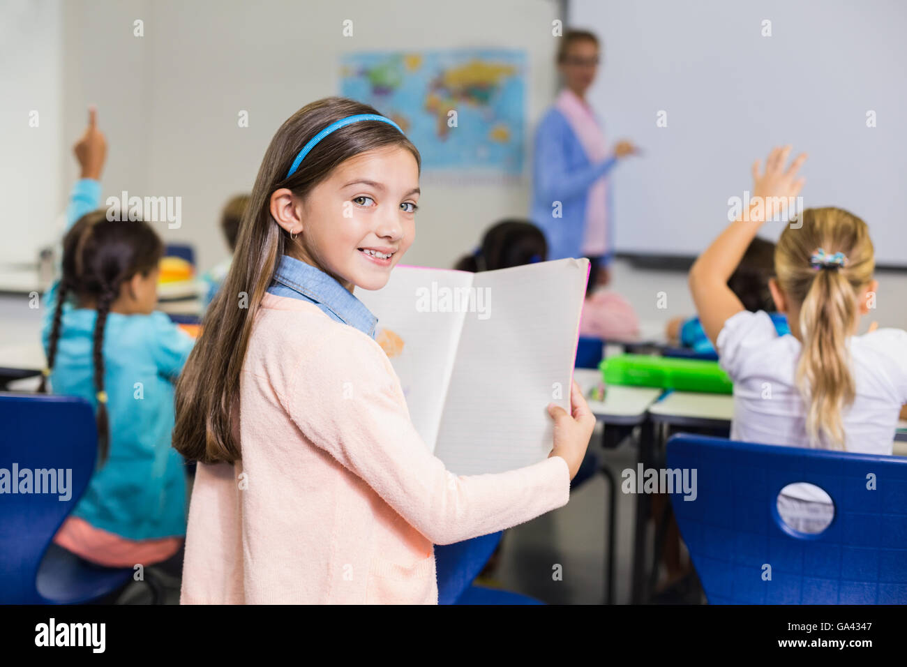 Portrait of schoolgirl standing with book in classroom Stock Photo - Alamy