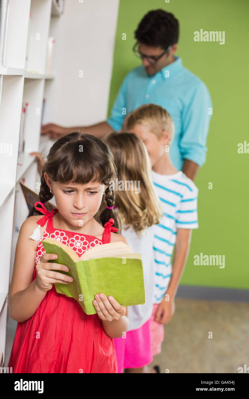 Schoolgirl reading book in library Stock Photo - Alamy