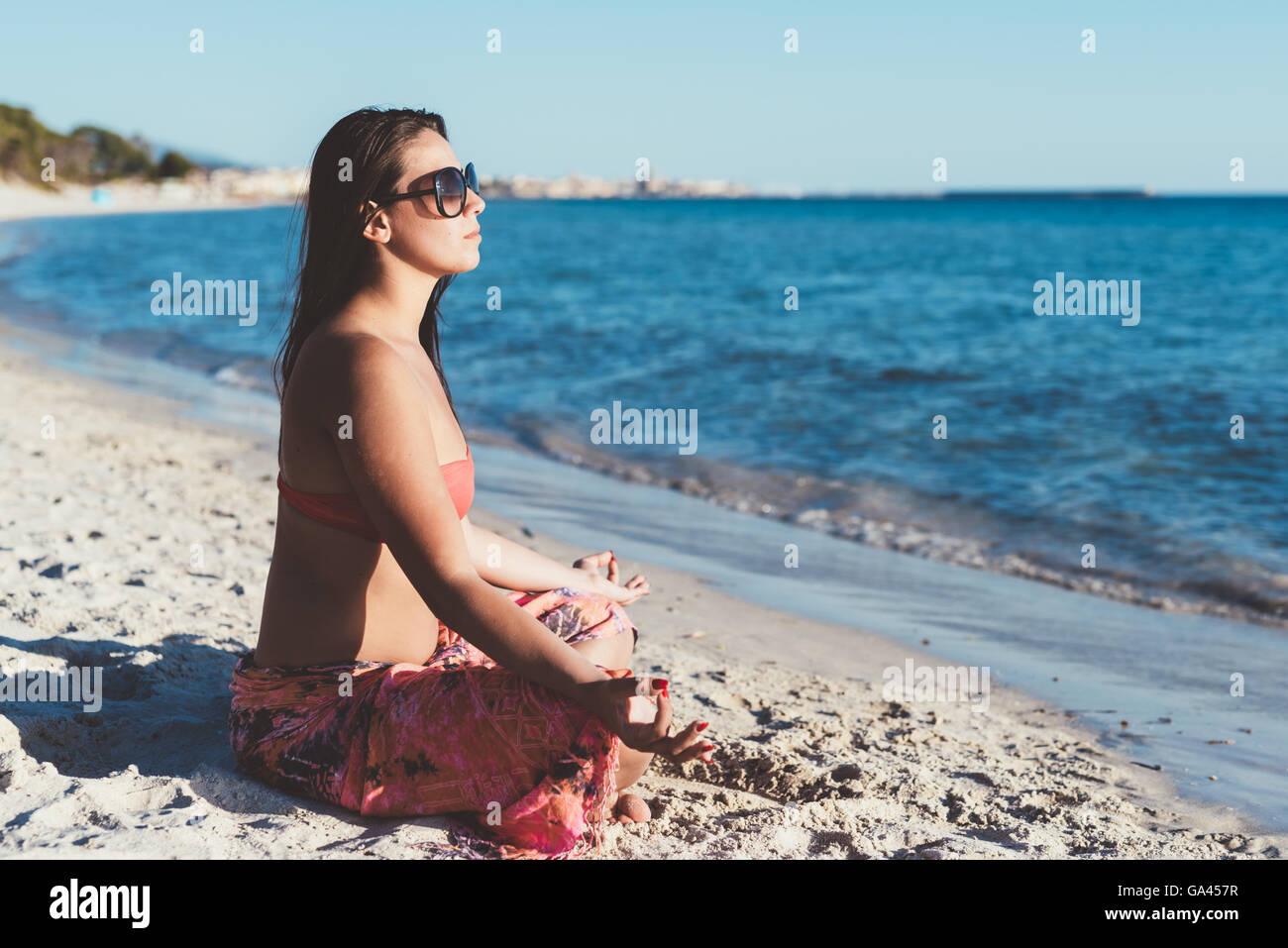 young beautiful woman doing yoga at the beach in summertime in lotus ...