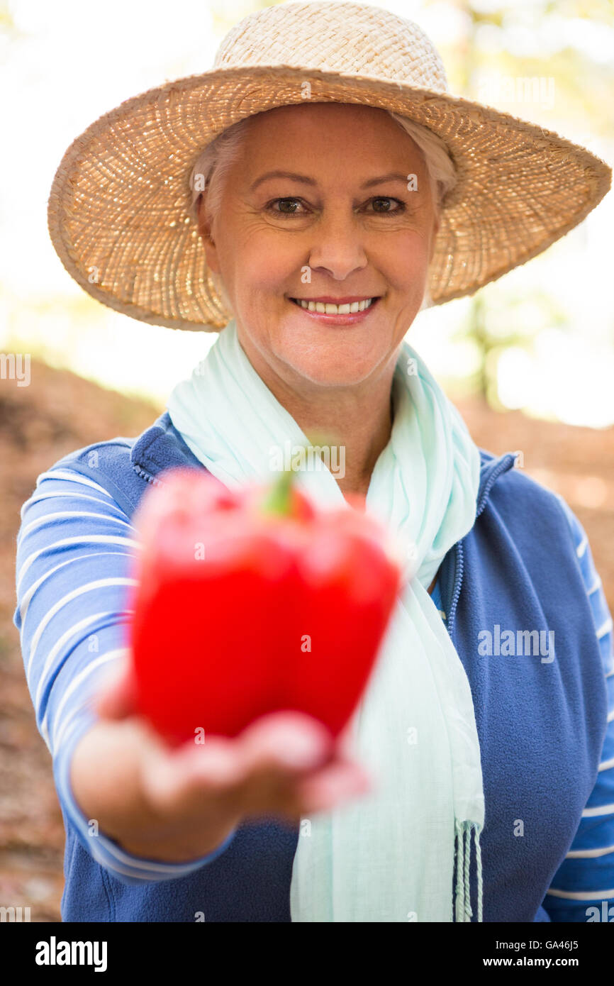 Portrait of happy gardener holding red bell pepper at garden Stock Photo