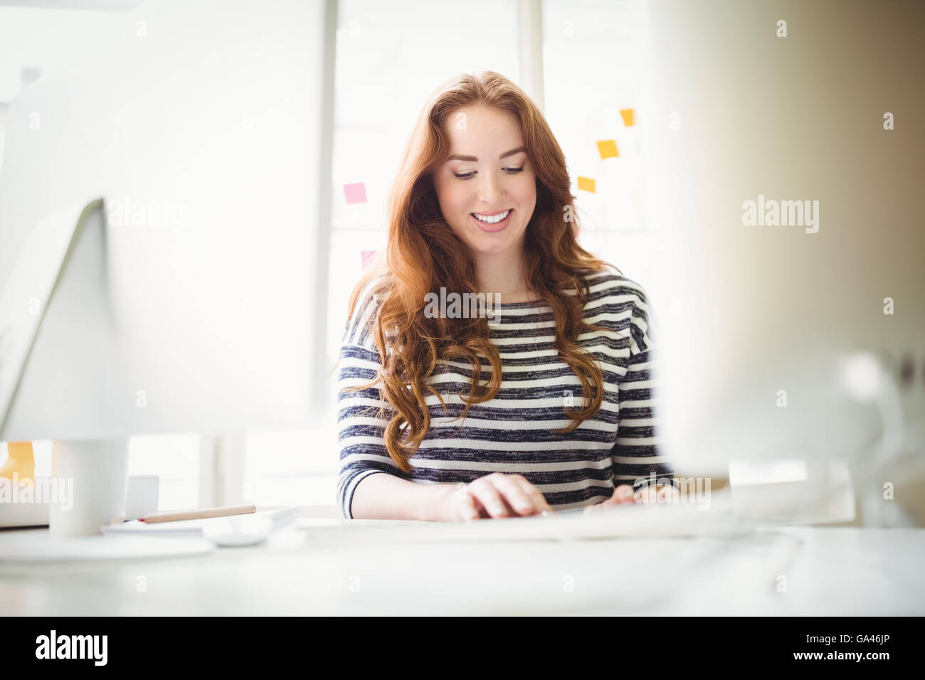 Happy businesswoman working at desk in creative office Stock Photo - Alamy