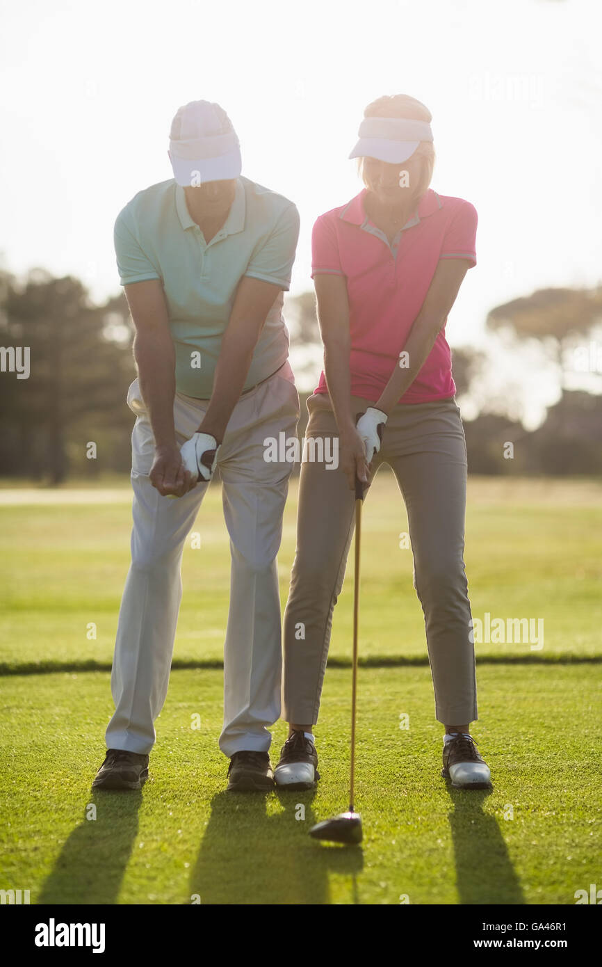 Full length of mature male golfer teaching woman Stock Photo