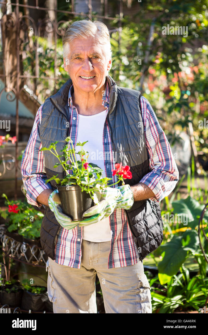 Portrait of confident gardener holding potted plant at garden Stock ...
