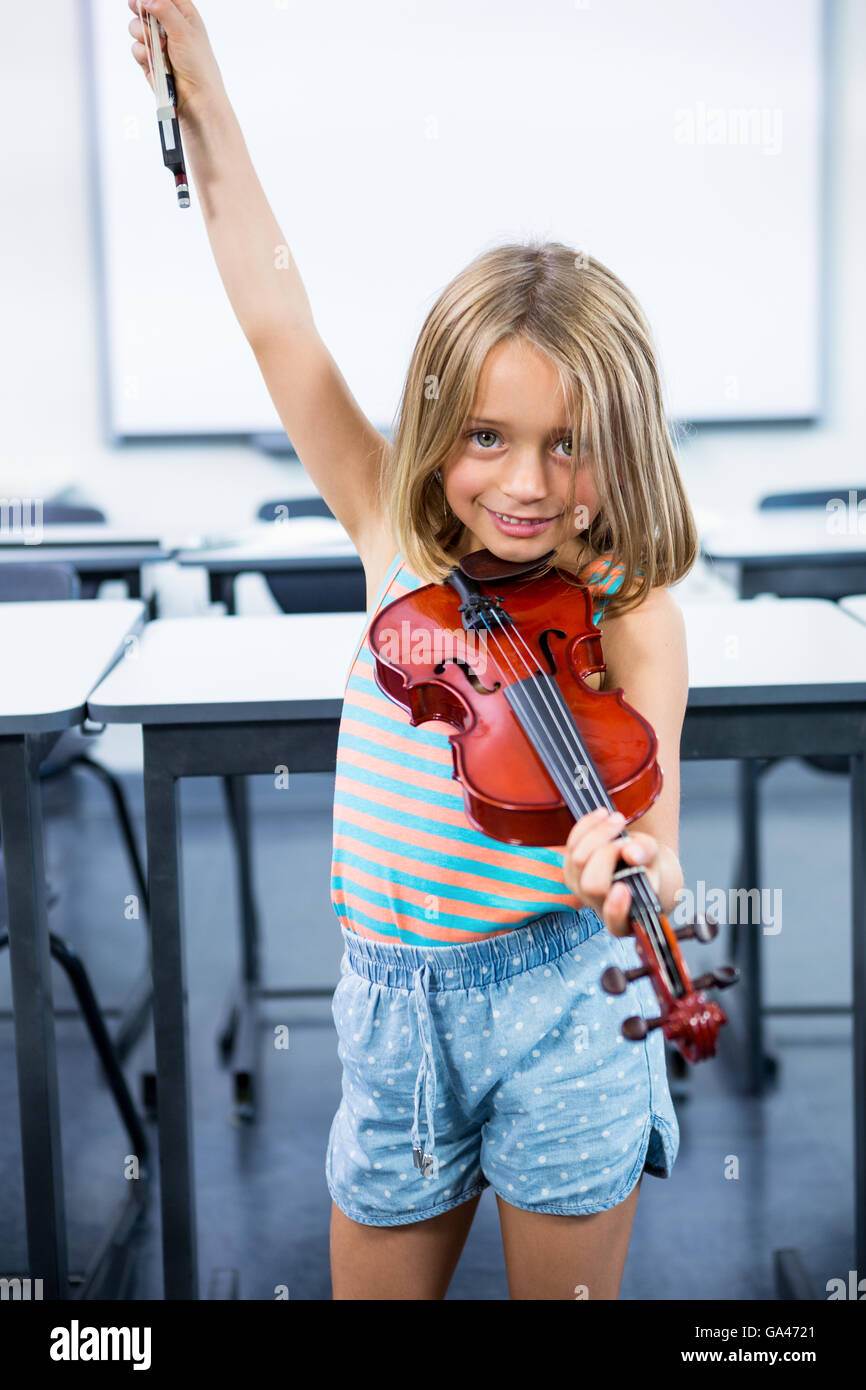 Happy girl playing violin in classroom Stock Photo