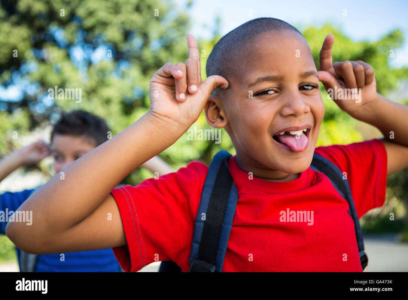 Playful schoolboy making a face at school campus Stock Photo