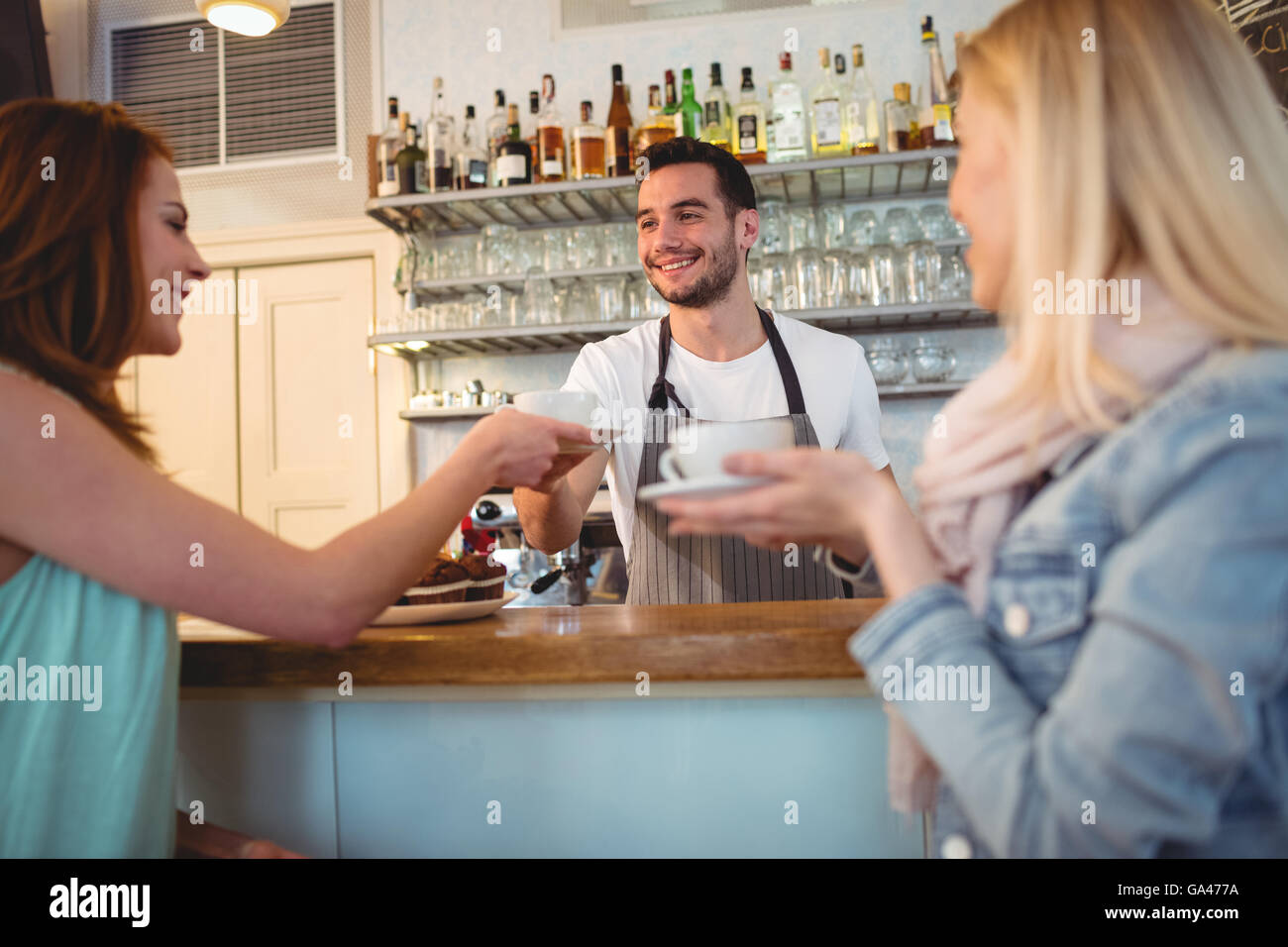 Happy waiter serving coffee to customer at cafeteria Stock Photo