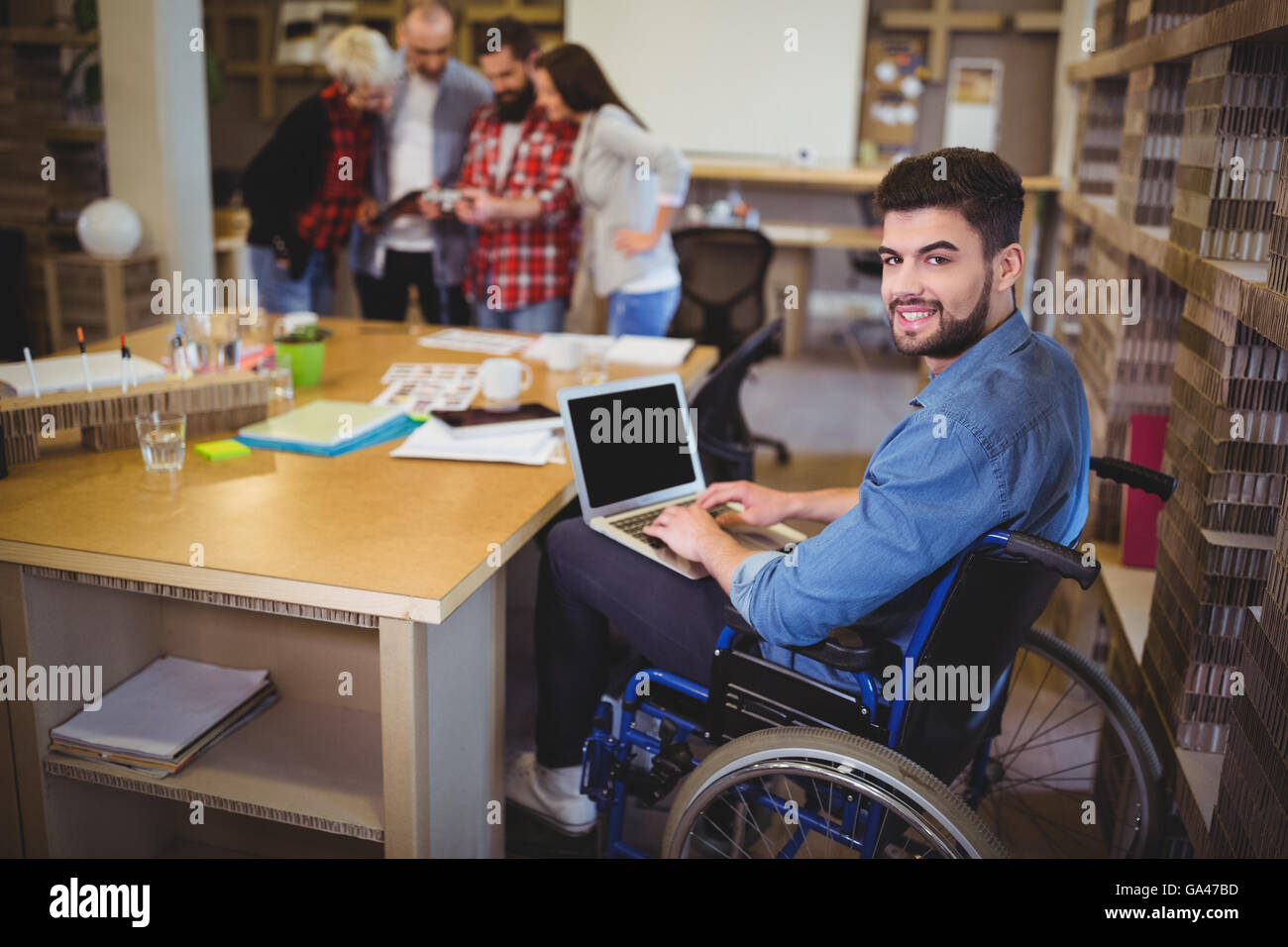 Confident disabled businessman using laptop at desk Stock Photo