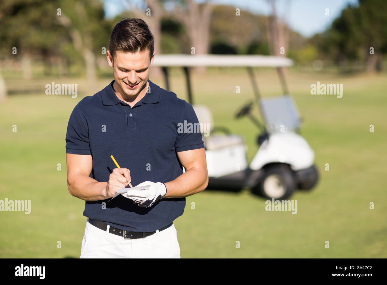 Smiling golfer writing on score card Stock Photo