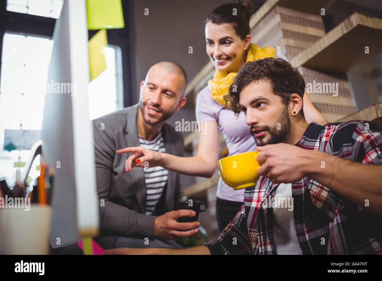 Businesswoman pointing while explaining male colleagues Stock Photo