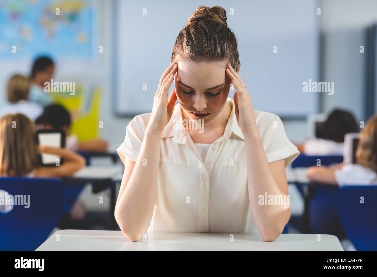 Depressed female teacher touching her head Stock Photo