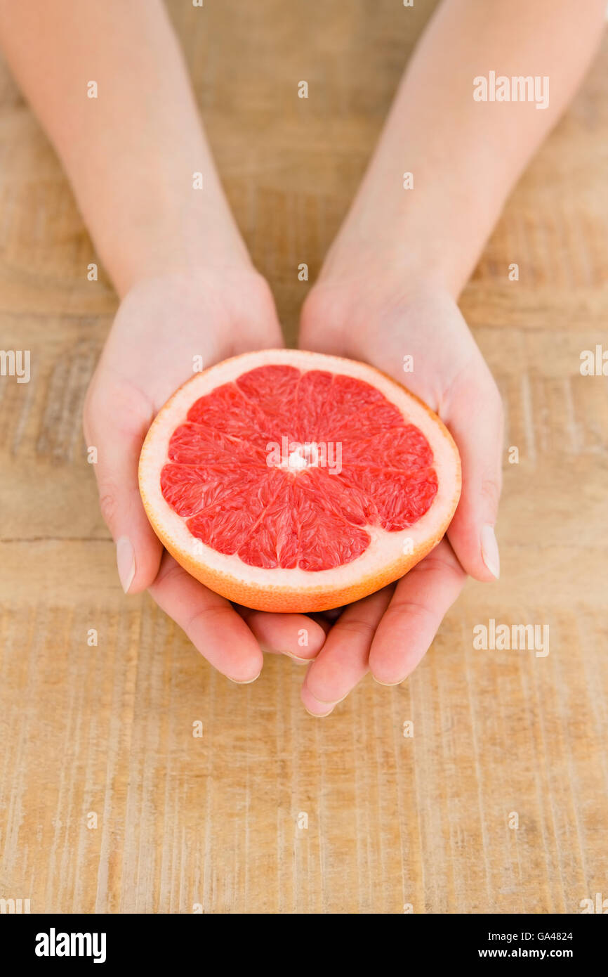 Person holding grapefruit slice at table Stock Photo Alamy
