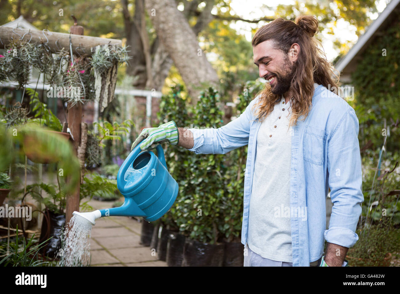 Happy gardener watering plants at community garden Stock Photo - Alamy