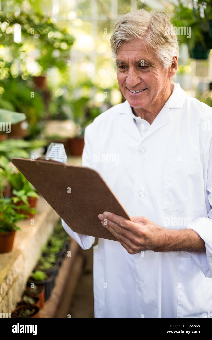Male scientist smiling while writing on clipboard Stock Photo