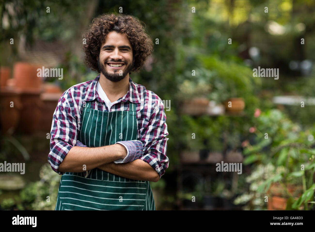 Confident male gardener standing at greenhouse Stock Photo