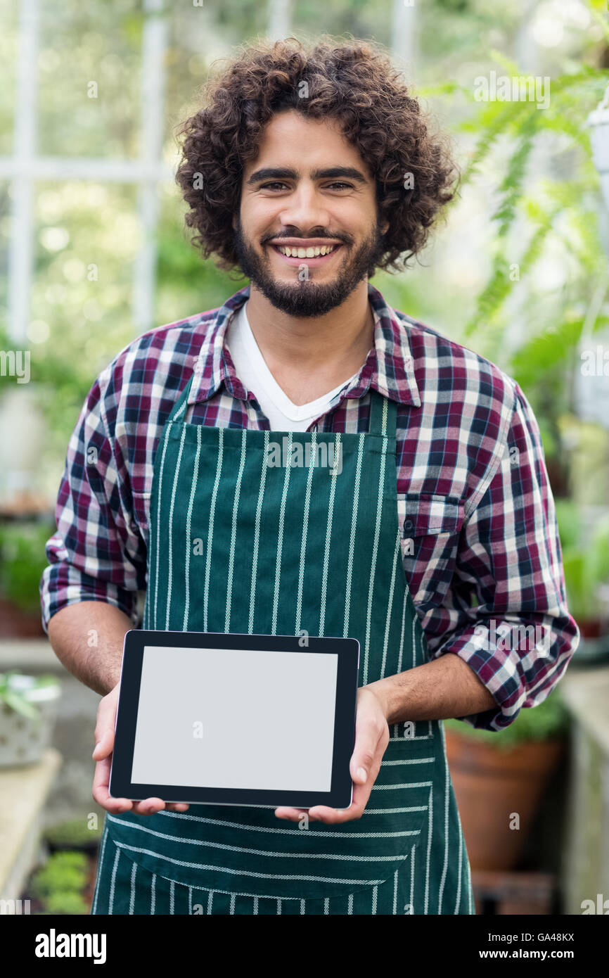 Male gardener showing digital tablet at greenhouse Stock Photo