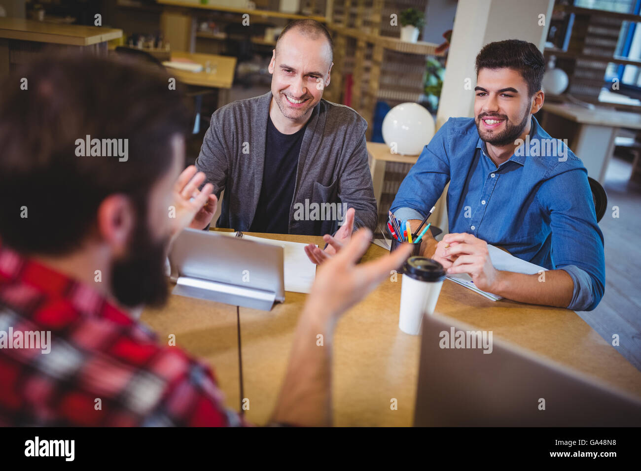 Business people smiling discussing at desk Stock Photo - Alamy