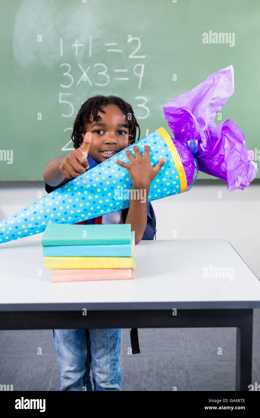 Boy holding gift at table in classroom Stock Photo