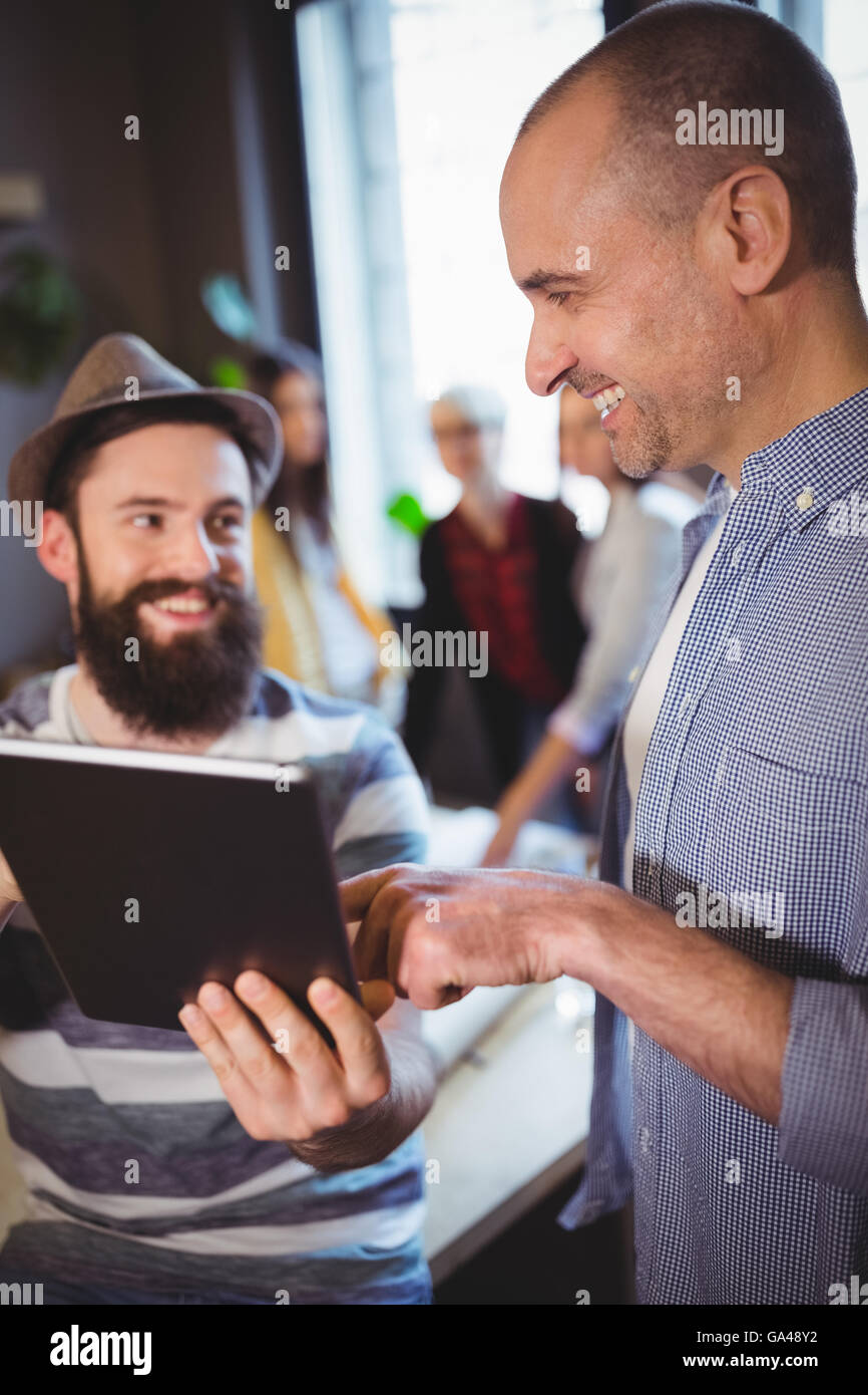 Happy male coworkers discussing over digital tablet Stock Photo