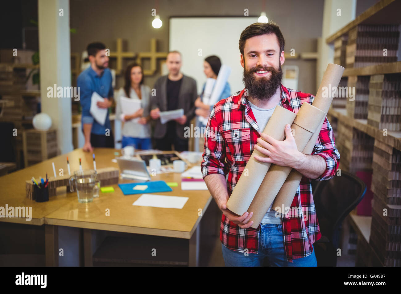 Architect holding blueprint tubes while standing by table Stock Photo