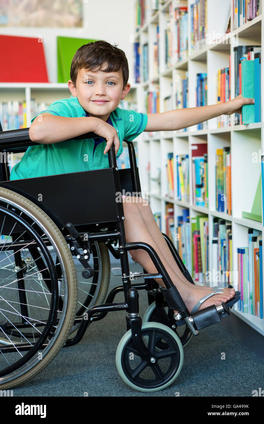 Elementary handicapped boy searching books in library Stock Photo