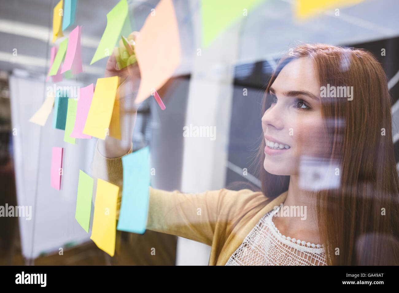Attractive businesswoman writing on sticky notes Stock Photo - Alamy