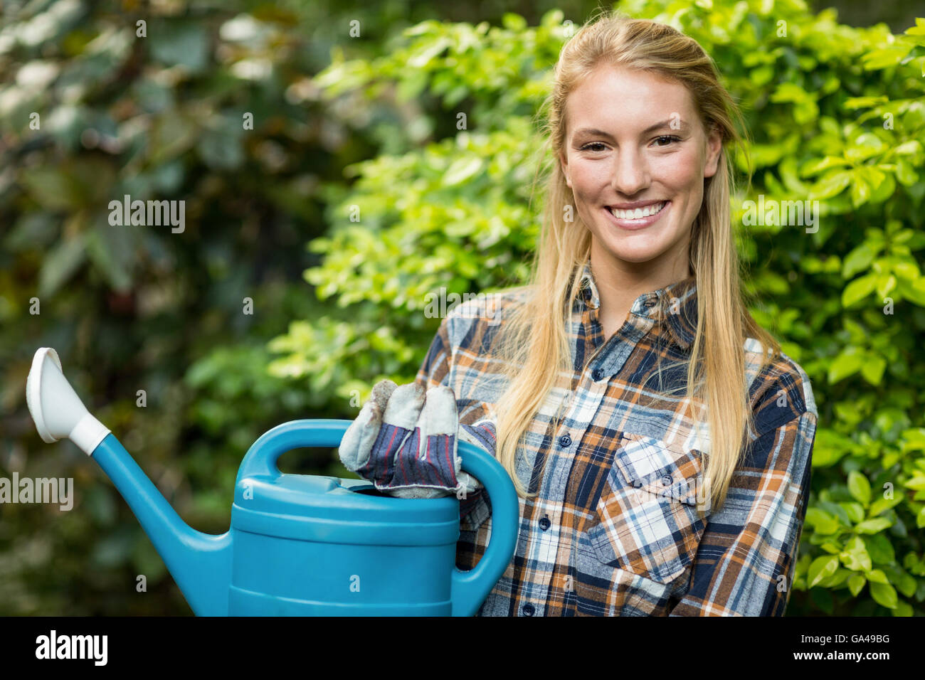Confident female gardener holding watering can Stock Photo - Alamy