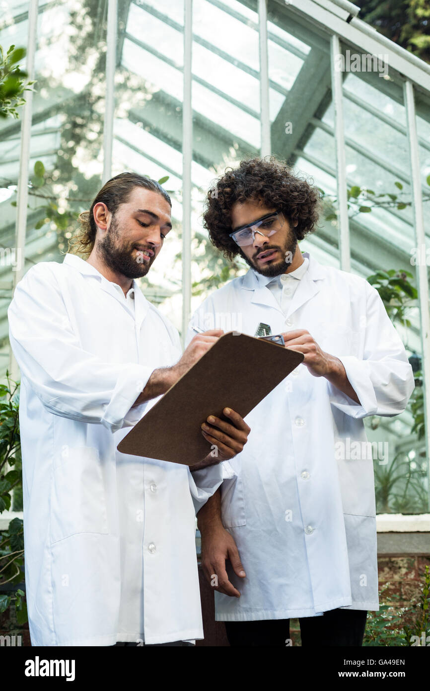 Male scientists discussing over clipboard Stock Photo