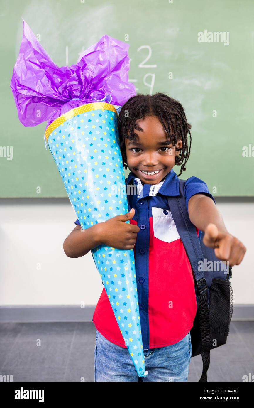 Happy boy holding gift in classroom Stock Photo