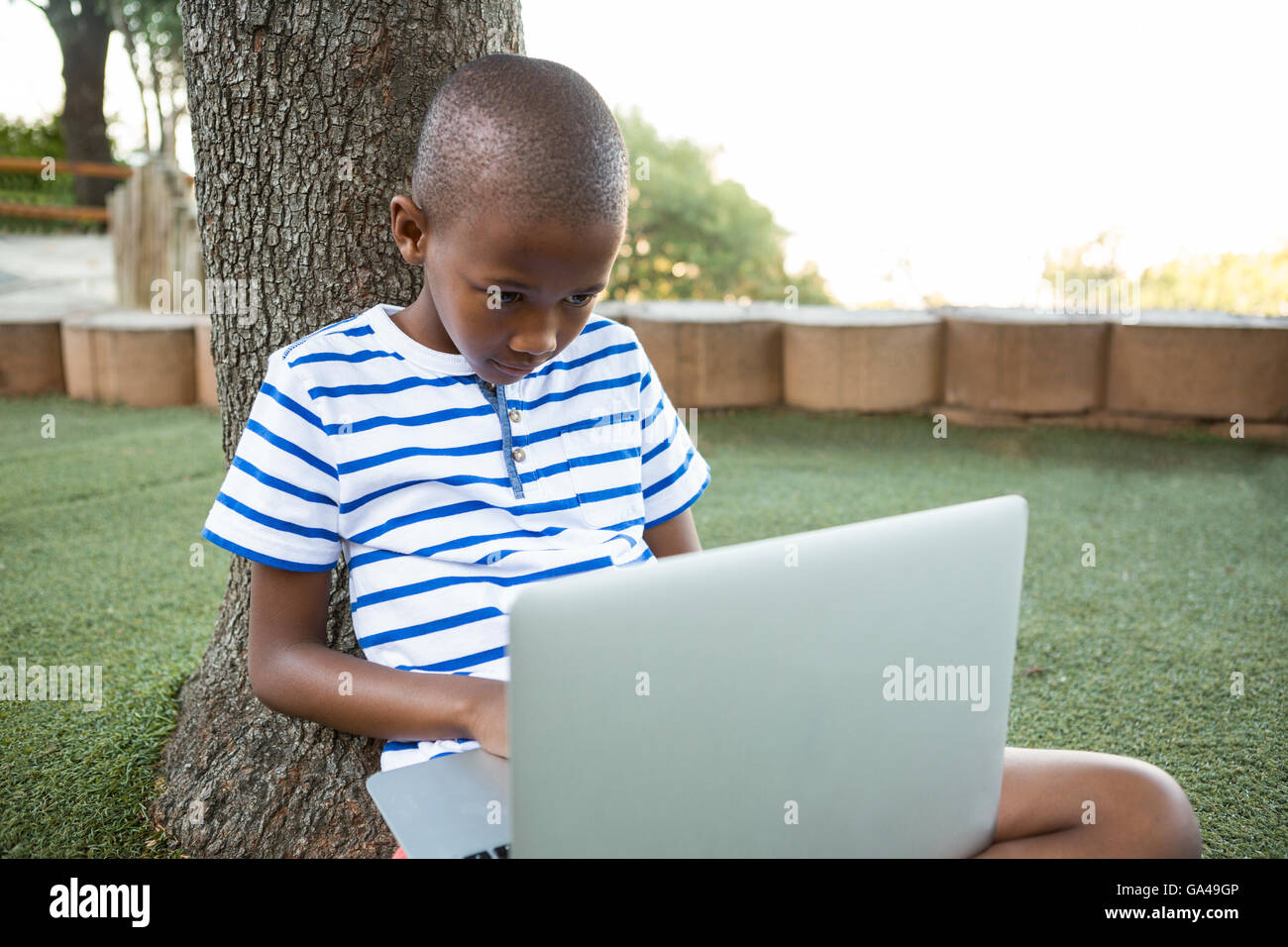 Elementary boy using laptop at park Stock Photo
