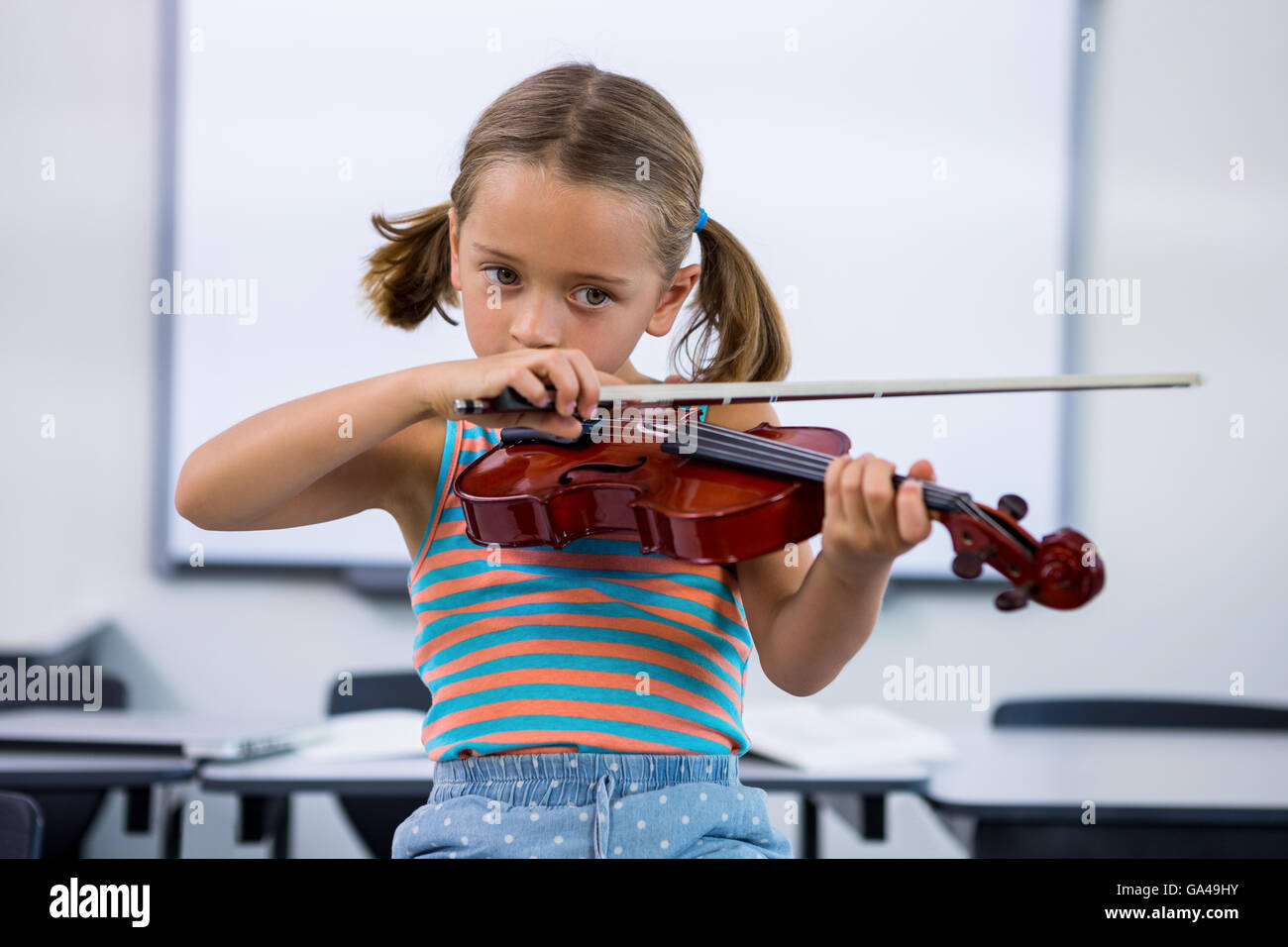 Girl playing violin in classroom Stock Photo