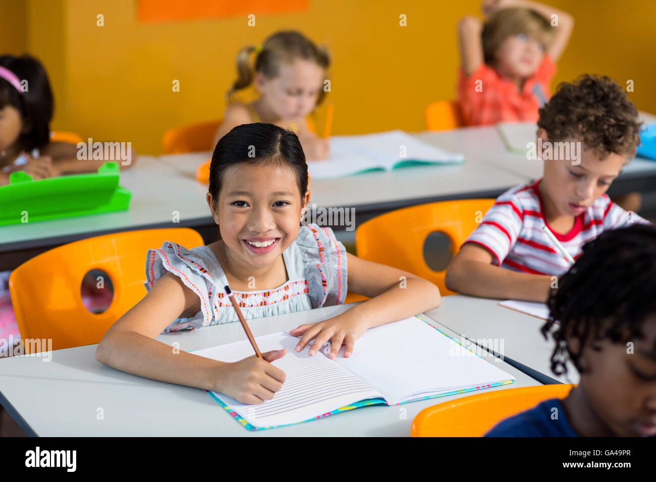 Portrait of smiling girl with book on bench Stock Photo - Alamy