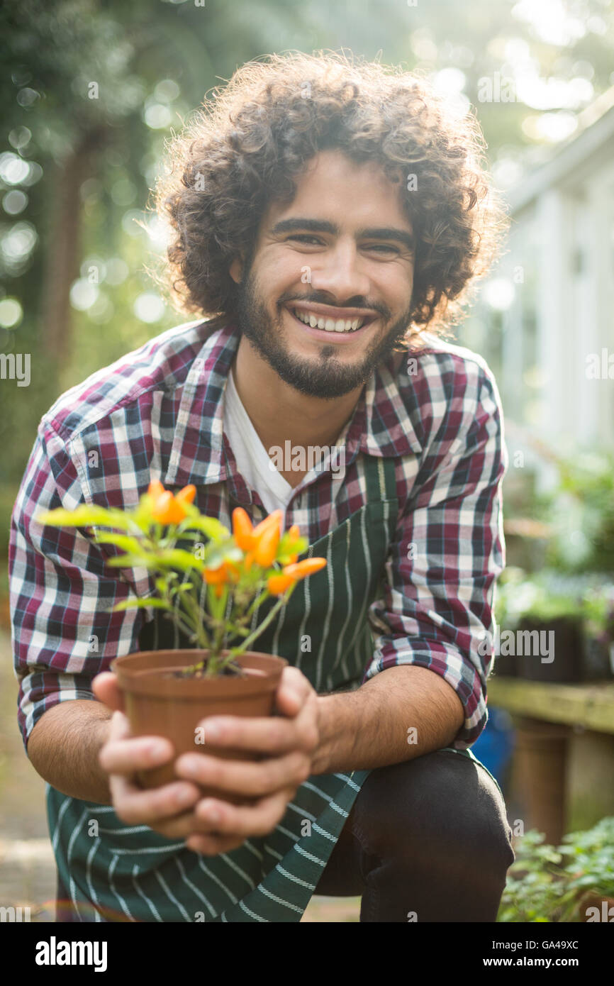 Gardener holding potted plant while kneeling Stock Photo - Alamy