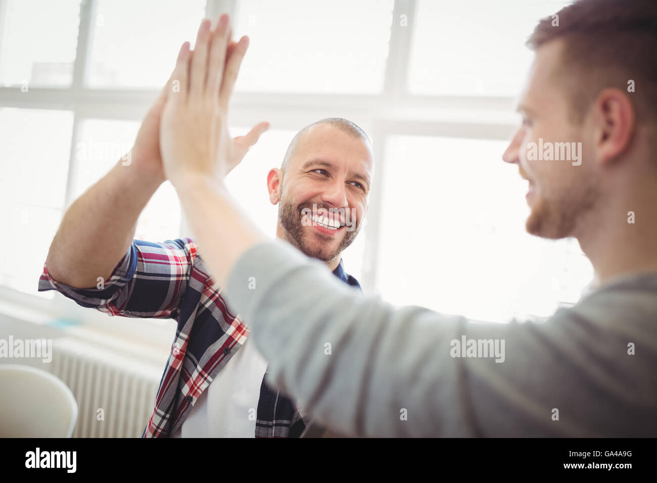 Male coworkers giving high-five Stock Photo