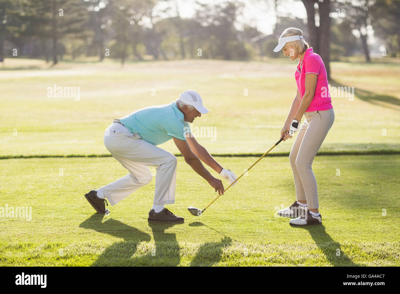 Mature male teaching woman to play golf Stock Photo