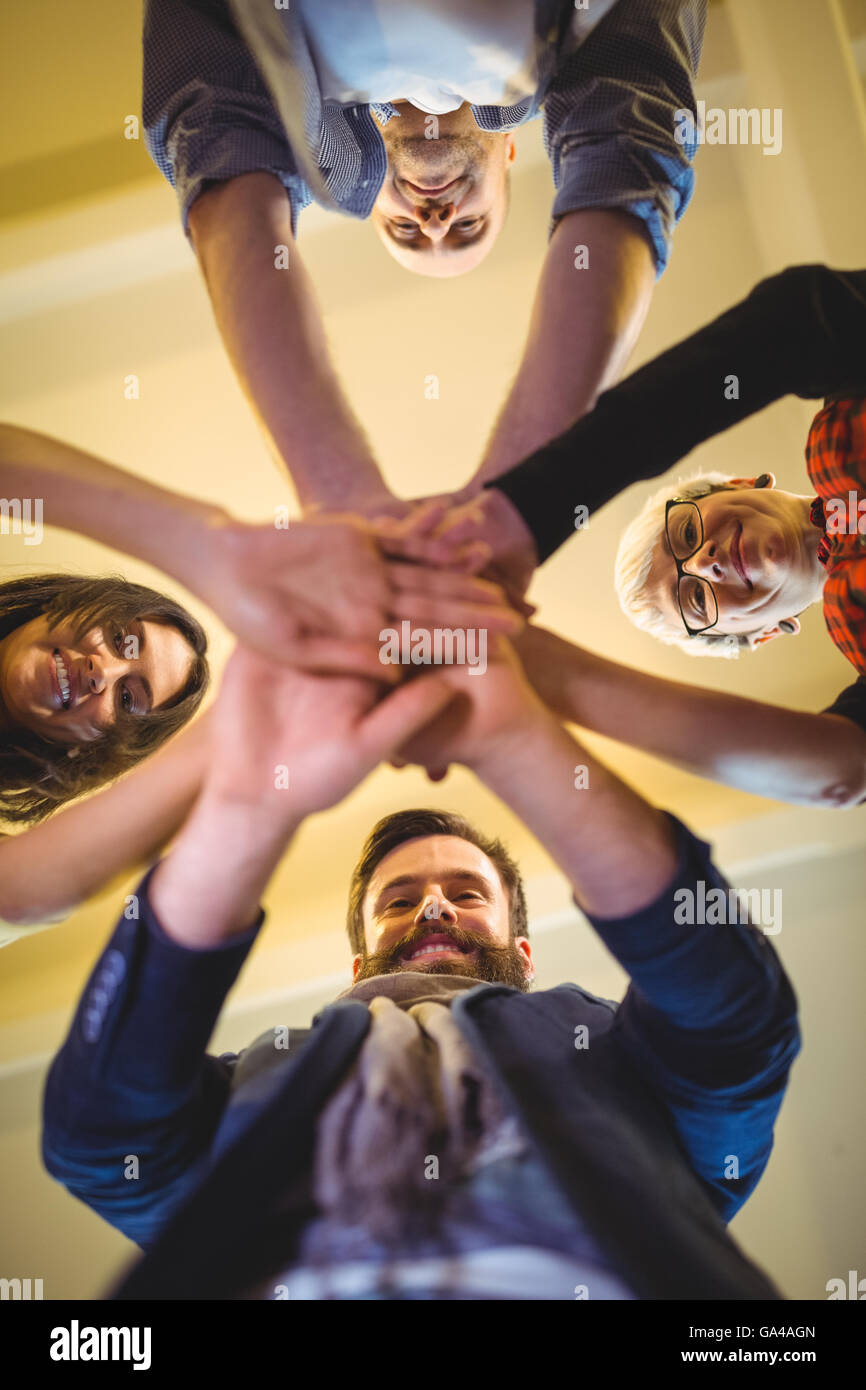 Happy business people stacking hands in creative office Stock Photo
