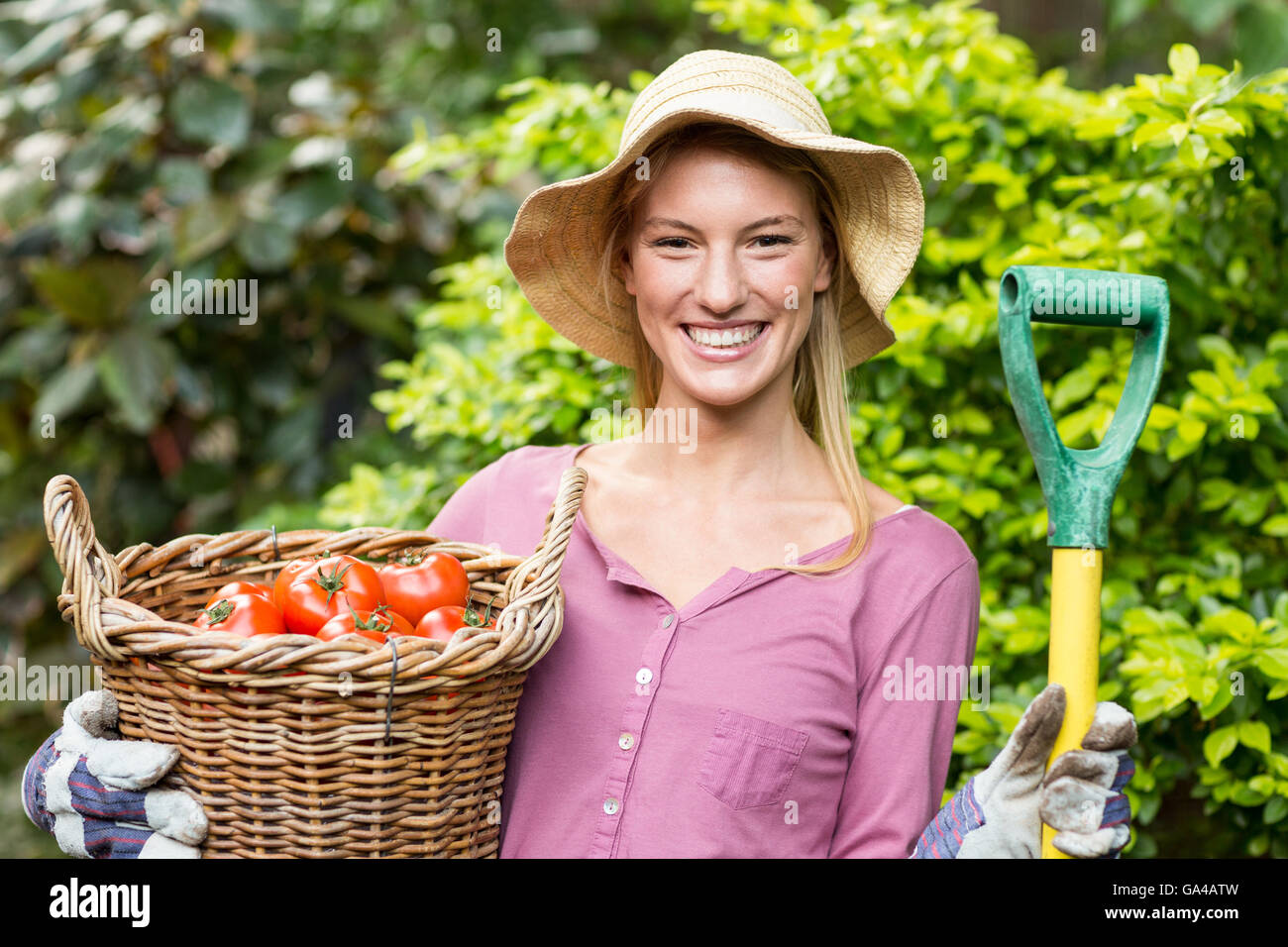 Female gardener holding tomato basket and work tool Stock Photo