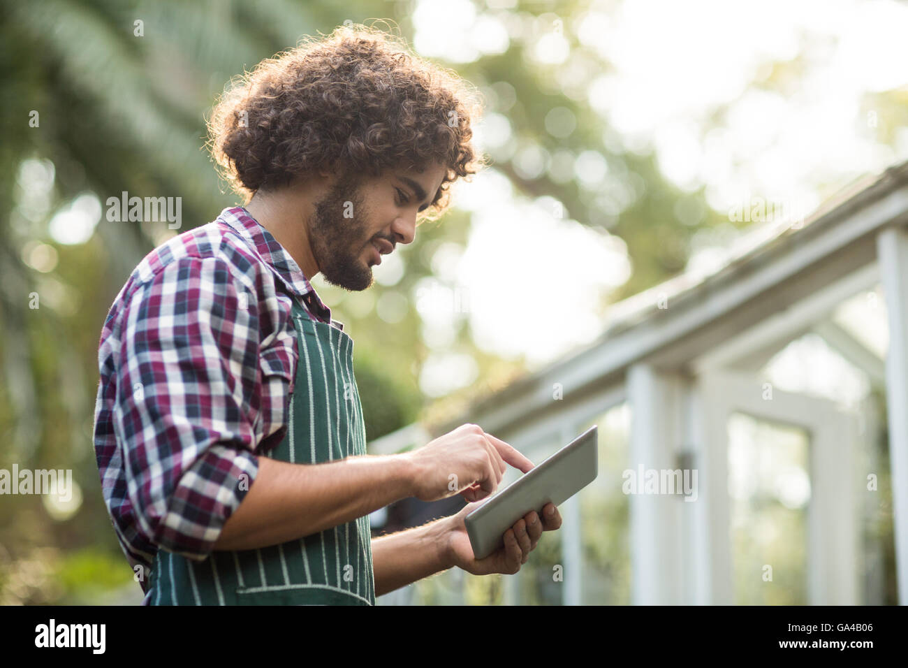 Male gardener using tablet computer outside greenhouse Stock Photo