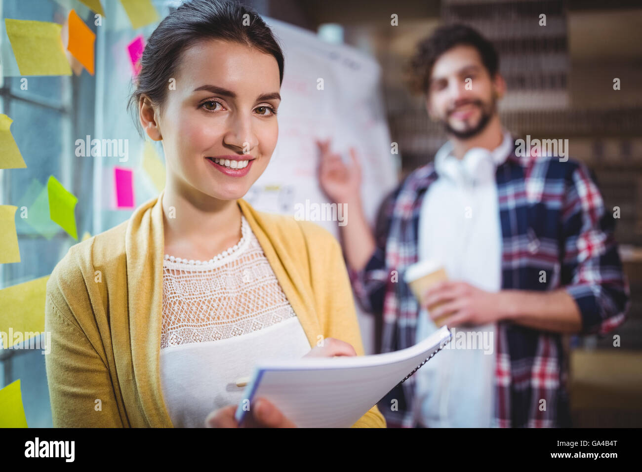 Businesswoman smiling while male colleague in background Stock Photo