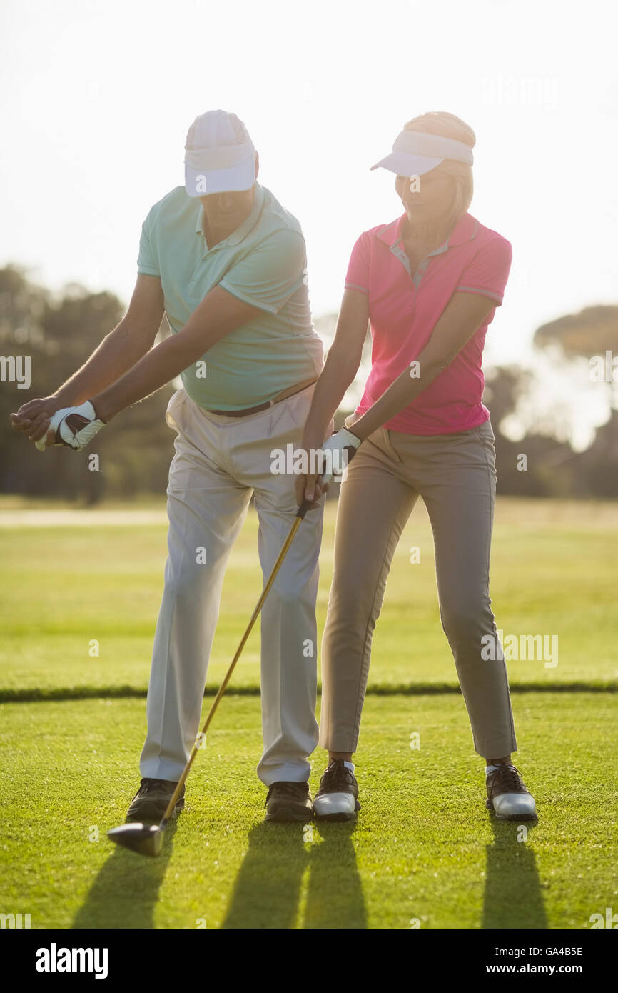 Full length of mature male golf player teaching woman Stock Photo