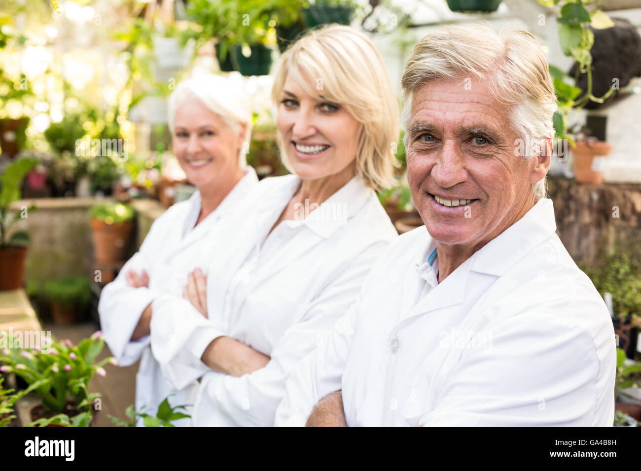 Confident male and female scientists at greenhouse Stock Photo