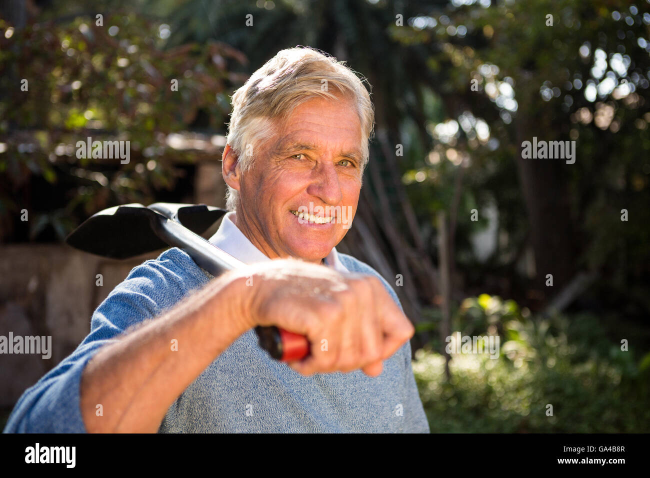Portrait of confident gardener carrying shovel on shoulder at garden ...
