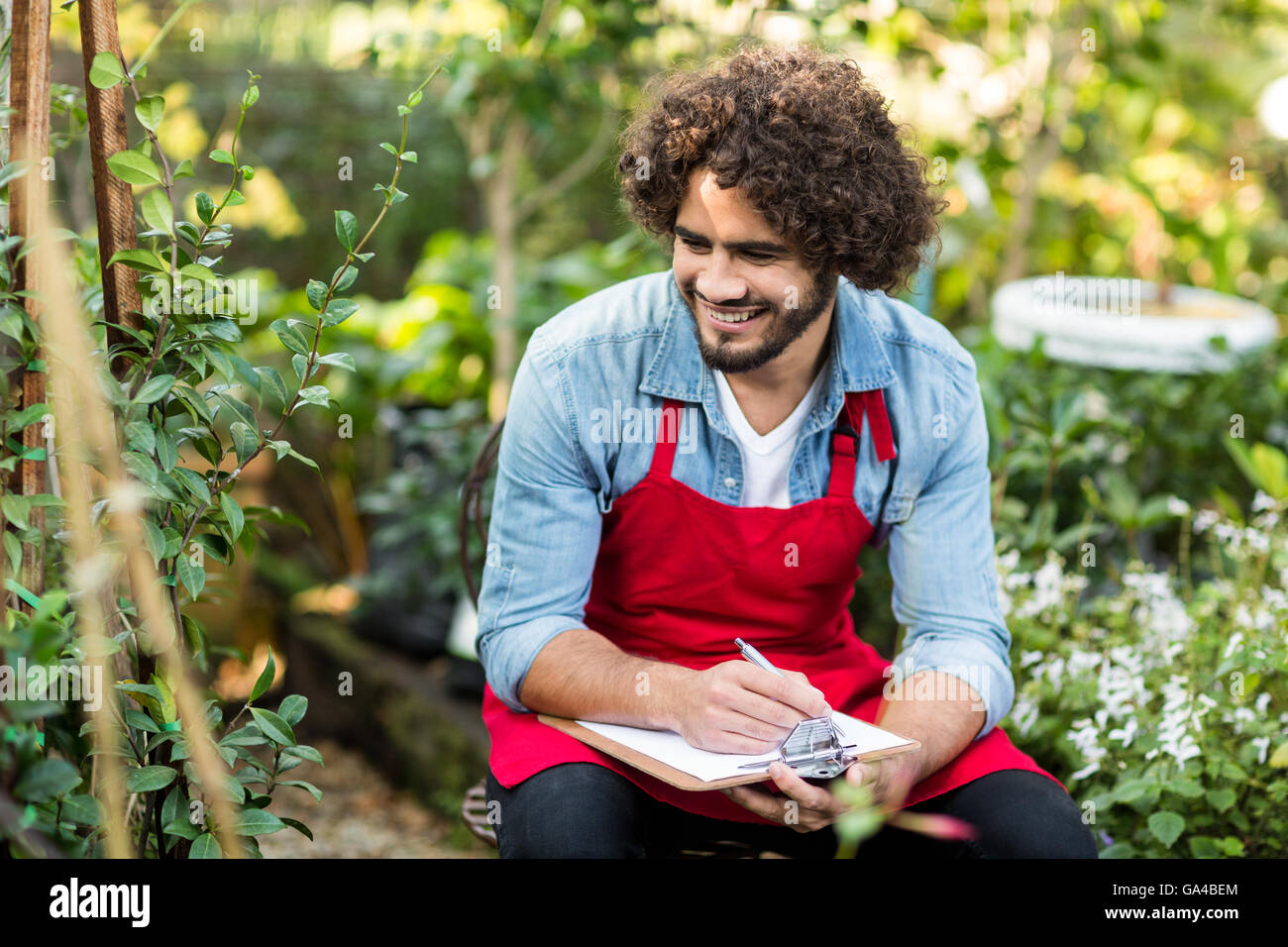 Smiling male gardener writing on clipboard Stock Photo