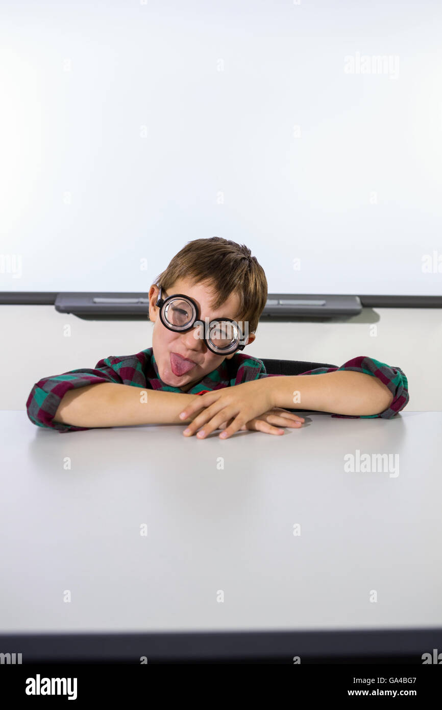 Playful boy making a face in classroom Stock Photo