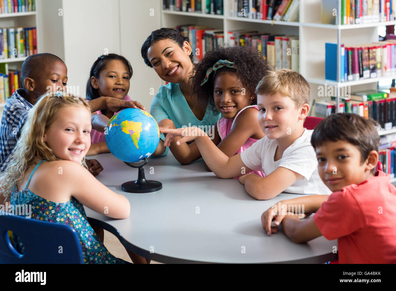 Female teacher and children with globe on table Stock Photo