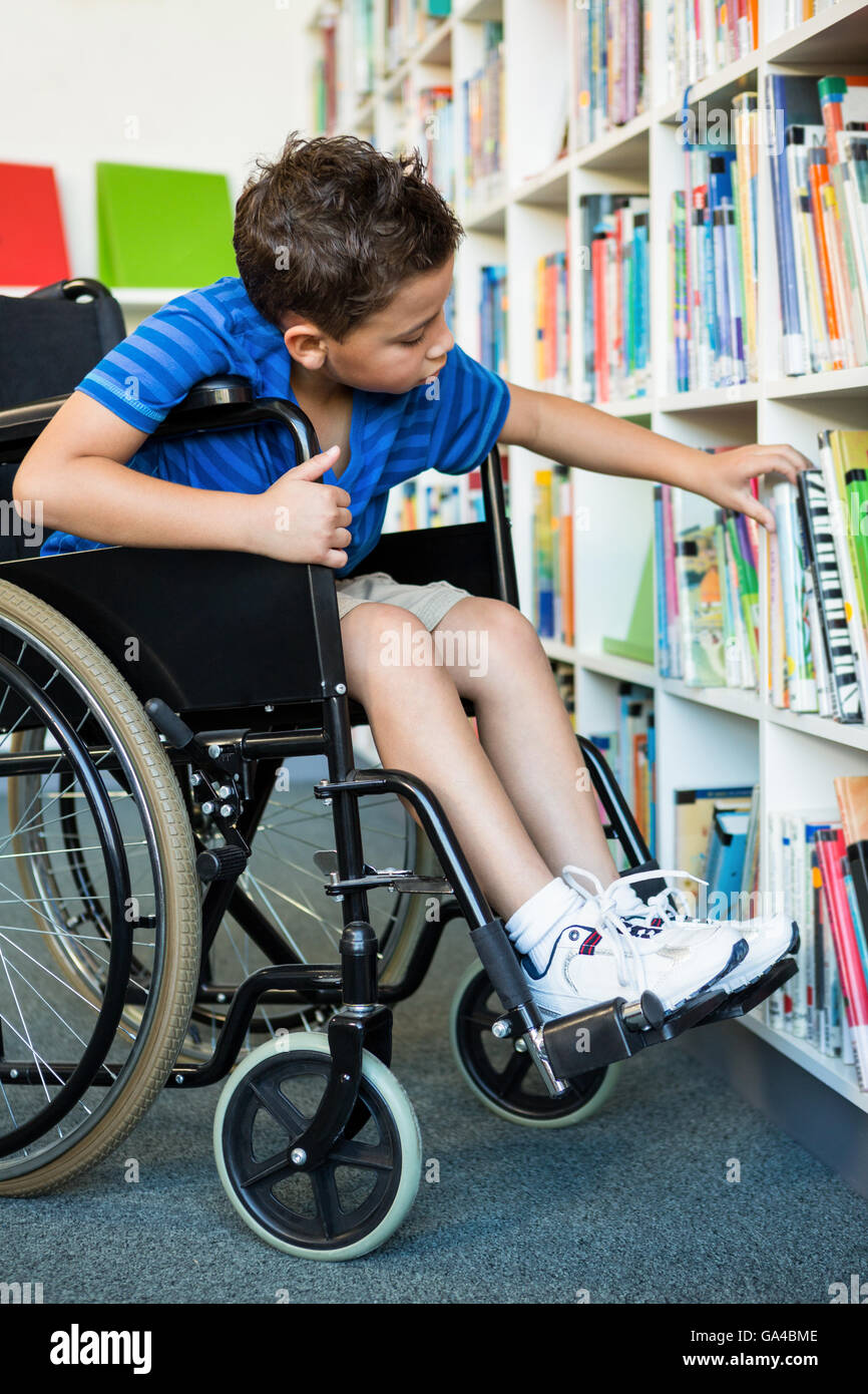 Handicapped boy searching books at library Stock Photo